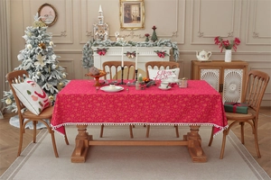 Macro view of red Christmas tablecloth with gold snowflakes and white pompom fringe