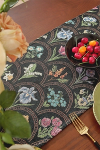 Gros plan du chemin de table jacquard avec motifs floraux vintage et pompons chic