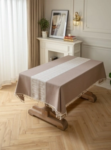 Detail of jacquard geometric wave patterns and fringe tassels on a beige tablecloth