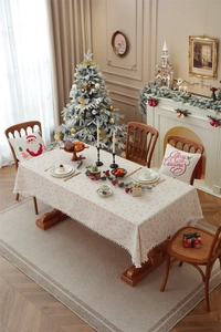 Close-up of festive Christmas tablecloth featuring golden snowflake patterns and white pom-poms