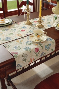 Détail d'un chemin de table en jacquard à fleurs sur une table en bois sombre