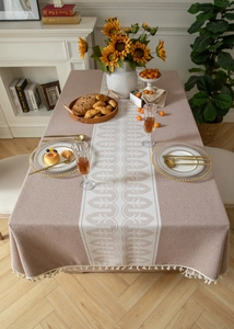 Detail of high-end jacquard tablecloth with beige ripple pattern and cotton tassels