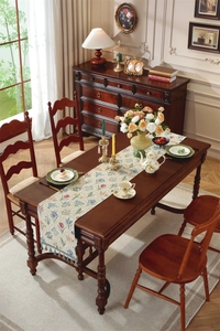 Détail du chemin de table vintage aux motifs floraux et pompons colorés sur bois