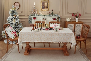 Close-up of Christmas tablecloth featuring gold deer patterns and white pom pom fringe