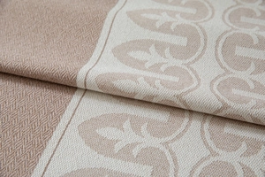 Detailed macro view of beige jacquard weave with fleur-de-lis geometric patterns