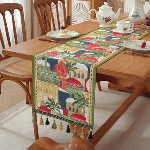 Green jacquard table runner with tassels featuring Middle Eastern city and palm tree patterns