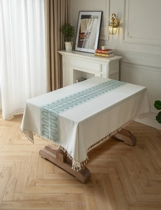 Detailed view of jacquard geometric wave tablecloth with fringe edges on wood table