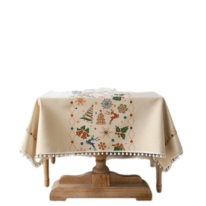 Christmas tablecloth with reindeer and tree patterns and white pom pom fringe edges