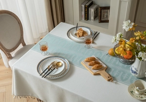 Detail of jacquard geometric wave tablecloth with fringe tassels and mint blue runner