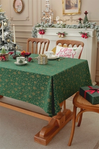 Close-up of green Christmas tablecloth with gold foil bells and snowflakes patterns