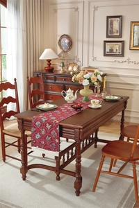 Détail du chemin de table vintage rouge avec motifs floraux et pompons blancs fins