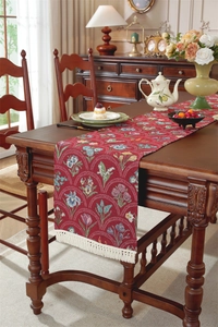 Vue détaillée du chemin de table vintage en jacquard rouge avec des pompons blancs