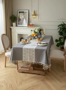 Detail of dark grey jacquard tablecloth with wave pattern runner and white cotton tassels