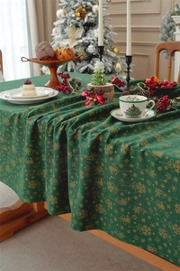 Detail of green Christmas tablecloth with gold bell patterns on a festive table setting