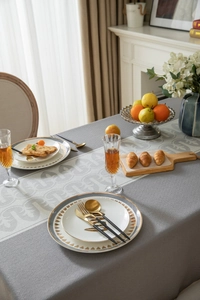 Detail of grey jacquard tablecloth with geometric damask patterns and textured tassels