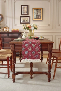 Détail d'un chemin de table rouge vintage avec motifs tulipes et pompons blancs