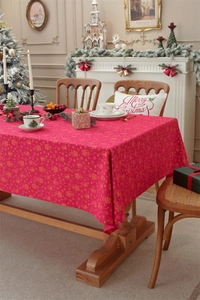 Detailed close-up of festive red Christmas tablecloth with golden bells and snowflake patterns