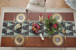 Detailed view of dark green Christmas table runner with festive tree and berry patterns