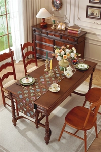 Gros plan d'un chemin de table vintage aux motifs floraux jacquard et finitions pompons
