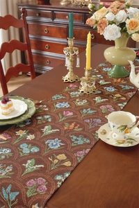 Détail d'un chemin de table jacquard à fleurs vintage avec glands sur bois massif