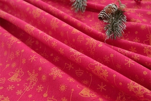 Close-up of red Christmas tablecloth featuring golden bells and festive snowflake patterns