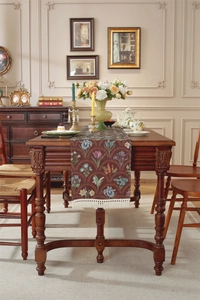 Gros plan du chemin de table vintage marron foncé avec jacquard floral et pompons blancs