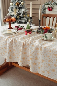 Close-up of Christmas tablecloth with gold snowflake and bell patterns on table