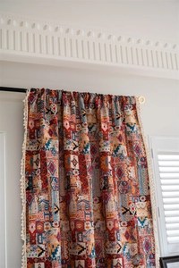Detail of bohemian patchwork curtain featuring colorful geometric patterns and cream tassels