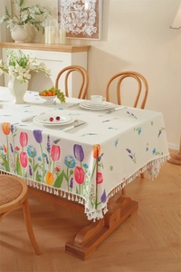 Close-up of floral tablecloth featuring vibrant tulips and elegant white fringe tassels
