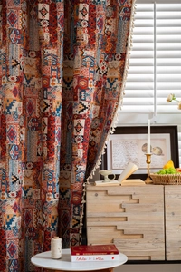 Detail of Bohemian curtain with ethnic pattern and white cotton tassels in cozy room
