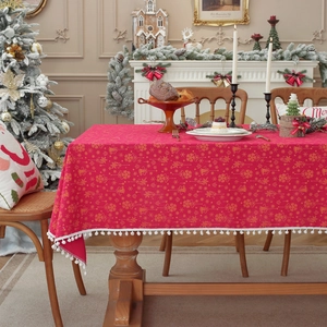 Red Christmas tablecloth with gold bell patterns and white pom-pom lace trim decor