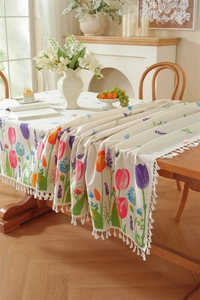 Detail of floral tulip print on rectangular tablecloth with decorative white tassels