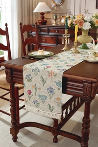Gros plan d'un chemin de table jacquard à fleurs vintage avec des franges beiges