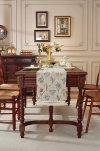 Détail d'un chemin de table en jacquard floral avec de délicats pompons blancs