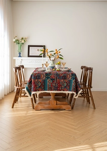 Close-up of bohemian floral jacquard tablecloth with white tassel edge on wooden table