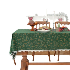 Green Christmas tablecloth with gold bells and reindeer pattern featuring white tassel edges