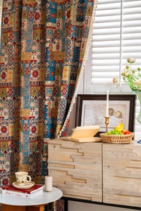 Detail of bohemian geometric pattern curtain with white pom-pom fringe and tassels