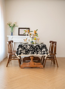 Close-up of black bohemian floral tablecloth with white fringe tassels on a dining table