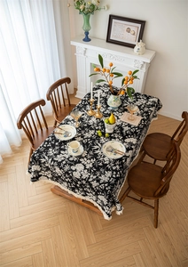 Detail of bohemian black and white floral tablecloth with elegant cream tassel edges