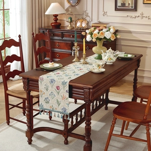 Chemin de table floral vintage avec pompons bleus sur une table en bois foncé chic