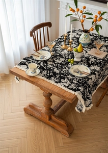 Detailed texture of jacquard floral tablecloth with elegant beige fringe on wooden table