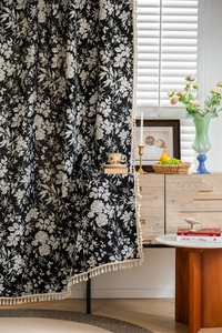 Detailed view of bohemian floral curtain fabric with decorative cream tassels