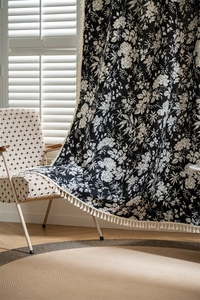 Detailed shot of black floral jacquard curtain fabric with decorative white cotton tassels