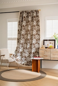 Close-up of bohemian curtain with white palm leaf print and cream tassel fringe