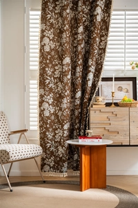 Detailed view of floral dark brown curtains with elegant white tassel fringe borders