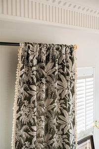 Detail of bohemian curtains with tropical leaf prints and decorative side tassels