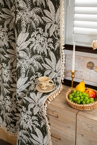 Detail of tropical palm leaf pattern curtain with elegant bohemian white tassels