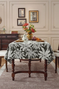Detail of bohemian tropical leaf jacquard tablecloth on vintage dark wood dining table