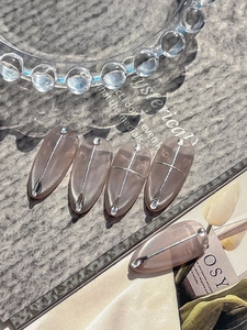 Detail of sheer pink cat-eye press-on nails with silver lines and tiny rhinestones