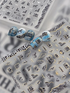 Detailed close-up of gold-stamped zebra print nail stickers with geometric heart patterns